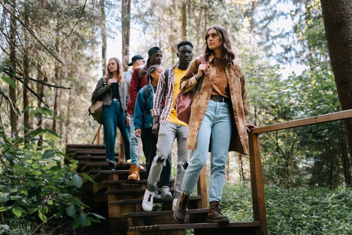 A diverse group of friends hiking down wooden steps in a lush forest setting.